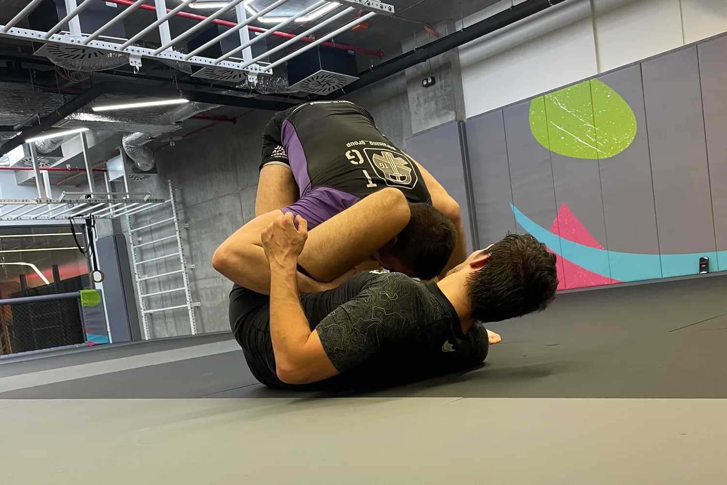Dvojica dospelých pri tréningu jiu-jitsu na žinenke v Elf Gyme